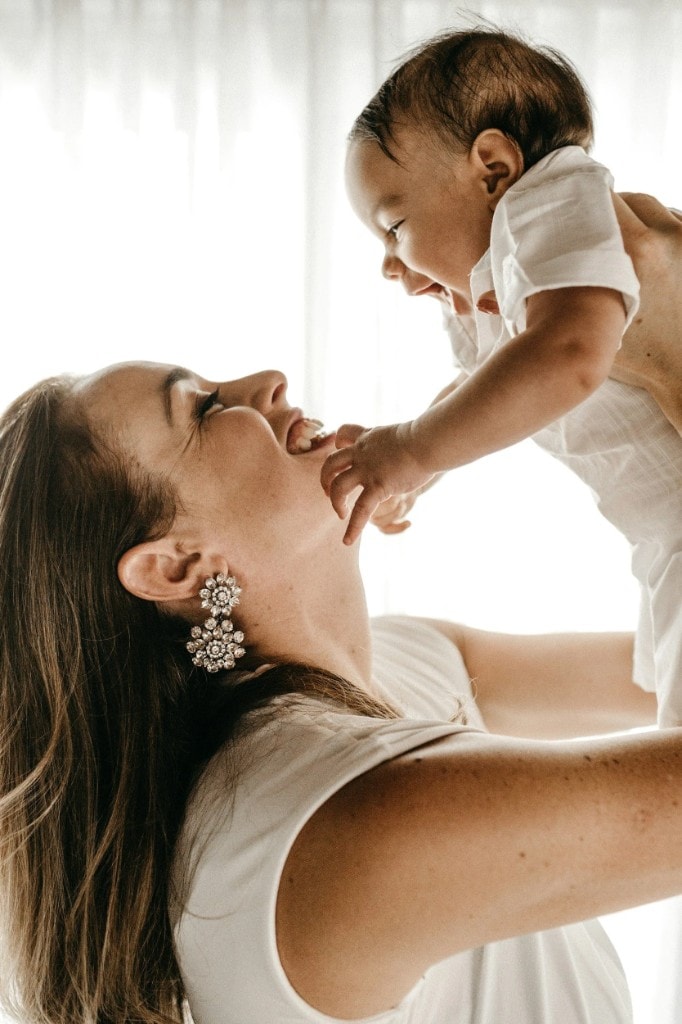 Mom lifting baby joyfully — therapy investment
