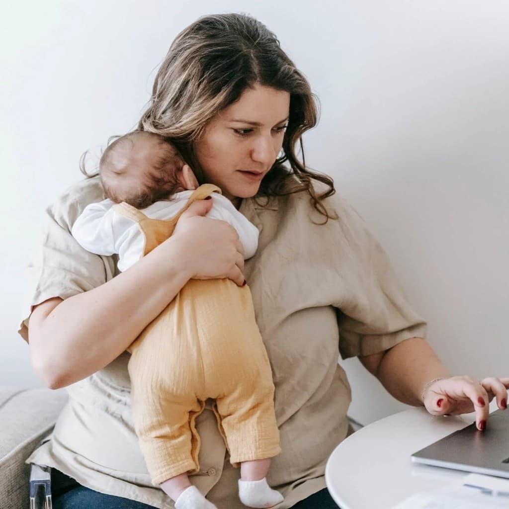 Mom holding baby while working — burnout therapy for moms